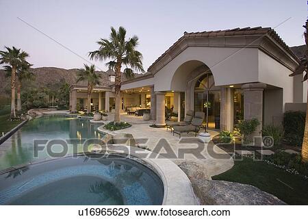 Stock Photo - Luxury swimming pool and house exterior at dusk. Fotosearch