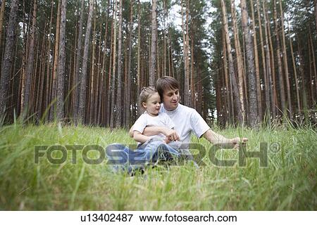Stock Photo - Man and girl sit in woodland clearing. Fotosearch