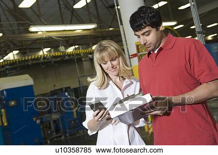 Stock Photography - Man and woman working in newspaper factory. Fotosearch