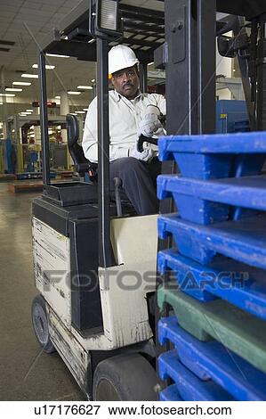 Stock Photo - Man driving fork lift truck in newspaper factory. Fotosearch