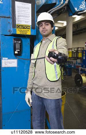Stock Photo - Man holding telephone out towards camera newspaper factory. Fotosearch