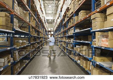 Stock Image - Man inspecting boxes in distribution warehouse. Fotosearch