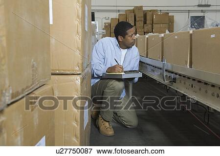 Man inspecting boxes on conveyor belt in distribution warehouse View Large Photo Image Stock Photo - Man inspecting boxes on conveyor belt in distribution warehouse. Fotosearch