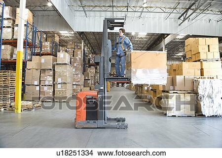 Picture - Man operating fork lift truck in distribution warehouse. Fotosearch