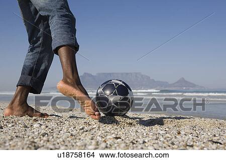 Man playing soccer on beach low section View Large Photo Image Picture - Man playing soccer on beach low section. Fotosearch