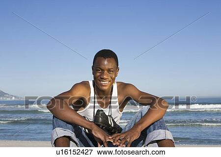 Man sitting on beach with with football boots round his neck View Large Photo Image Stock Photo - Man sitting on beach with with football boots round his neck. Fotosearch