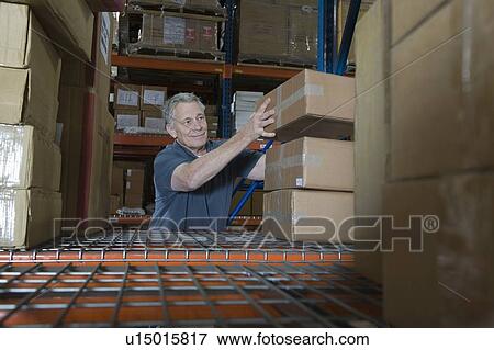 Stock Photo - Man stacking boxes in distribution warehouse. Fotosearch