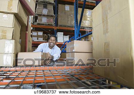 Stock Photo - Man stacking boxes in distribution warehouse. Fotosearch