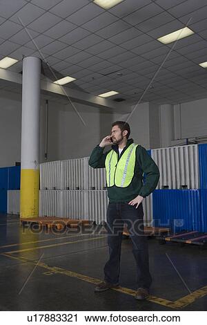 Man standing in factory using telephone View Large Photo Image Stock Image - Man standing in factory using telephone. Fotosearch