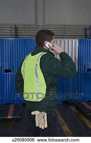 Man standing in factory using telephone View Large Photo Image Stock Photograph - Man standing in factory using telephone. Fotosearch