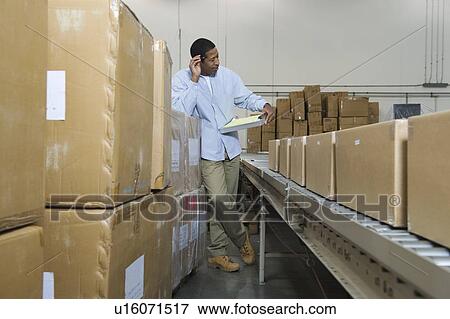Man standing next to conveyor belt in distribution warehouse View Large Photo Image Stock Photo - Man standing next to conveyor belt in distribution warehouse. Fotosearch