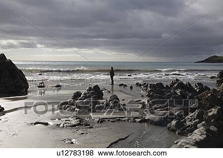 Stock Photo - Man stands at waters edge. Fotosearch