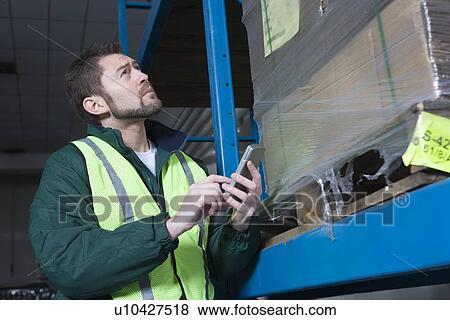 Stock Photo - Man using calculator in factory. Fotosearch