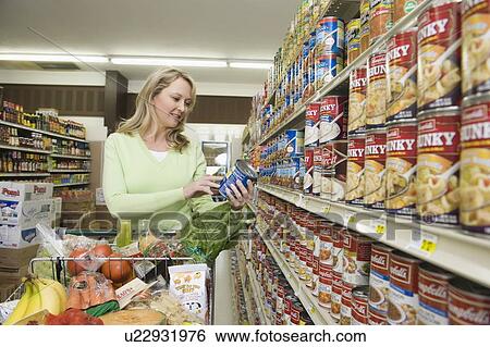 Mature woman selects tinned goods in supermarket aisle View Large Photo Image Stock Photograph - Mature woman selects tinned goods in supermarket aisle. Fotosearch