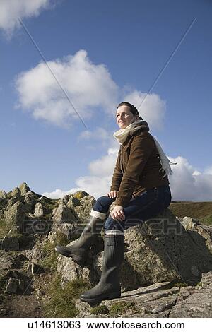 Stock Image - Mature woman sitting on a rock. Fotosearch