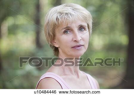 Mature woman stands in forest looking at camera View Large Photo Image Stock Photograph - Mature woman stands in forest looking at camera. Fotosearch