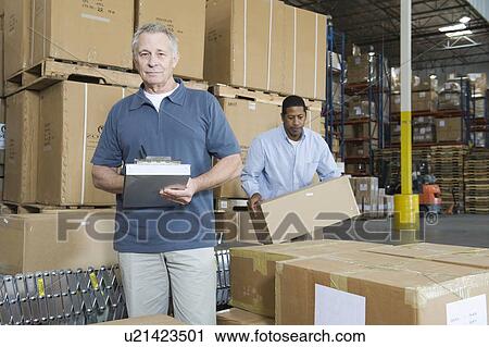 Stock Image - Men working in distribution warehouse. Fotosearch