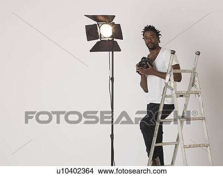 Picture - Mid adult (30-35 years) photographer in studio. Fotosearch