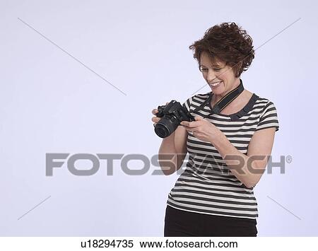 Mid adult woman holding digital camera studio shot View Large Photo Image Stock Photography - Mid adult woman holding digital camera studio shot. Fotosearch