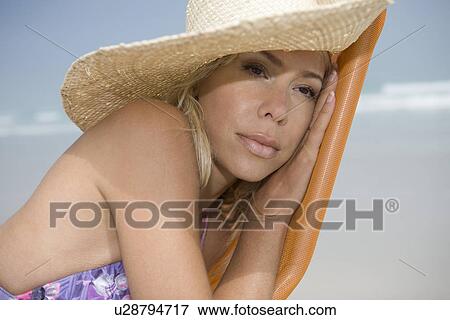Stock Photo - Mid adult woman leaning on deckchair and daydreaming. Fotosearch