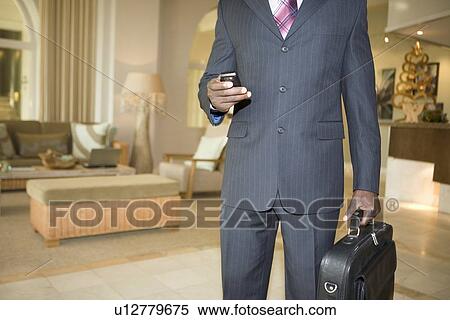 Mid section of Business man holding briefcase and mobile phone View Large Photo Image Stock Photography - Mid section of Business man holding briefcase and mobile phone. Fotosearch