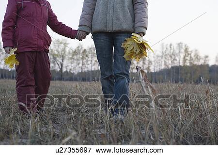 Stock Photo - Mother and daughter holding hands in field. Fotosearch