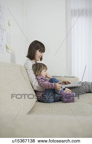 Mother and daughter with laptop in living room View Large Photo Image Stock Photo - Mother and daughter with laptop in living room. Fotosearch