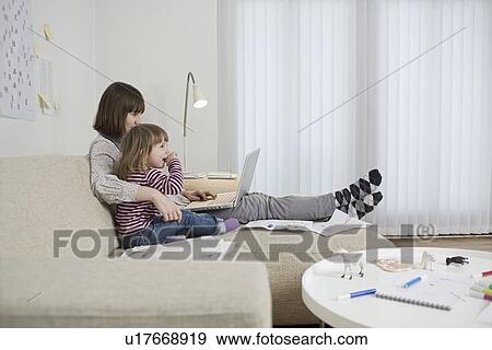 Mother and daughter with laptop in living room View Large Photo Image Stock Photo - Mother and daughter with laptop in living room. Fotosearch