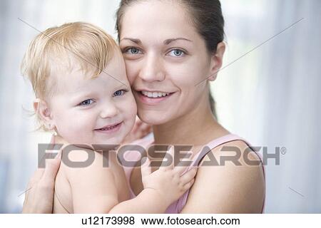 Stock Photo - Mother holds blonde toddler with pride. Fotosearch