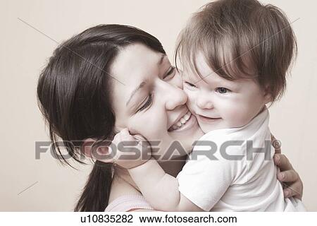 Stock Image - Mother laughs and squeezes her toddler. Fotosearch
