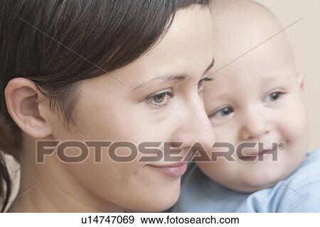 Stock Photo - Mother smiles holding baby. Fotosearch