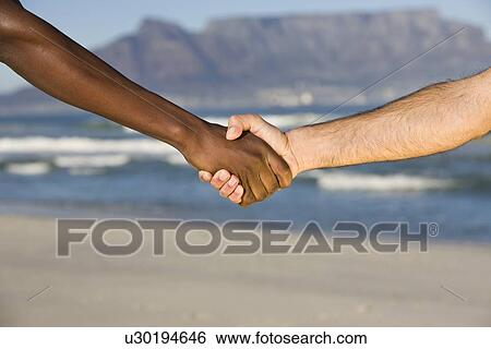 Stock Photograph - Multi-racial handshake Table MOuntain beach. Fotosearch