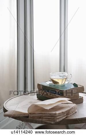 Stock Image - Open book on table with herbal tea. Fotosearch