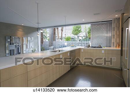 Stock Image - Open plan kitchen furnished in light wood Palm Springs. Fotosearch