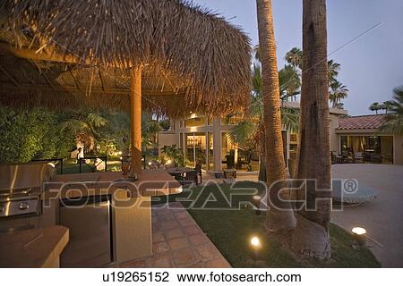 Stock Image - Outdoor bar counter alongside modern home dusk. Fotosearch