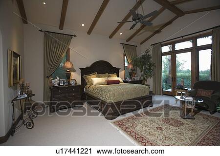 Stock Image - Palm Springs bedroom with beamed ceiling and patio doors. Fotosearch
