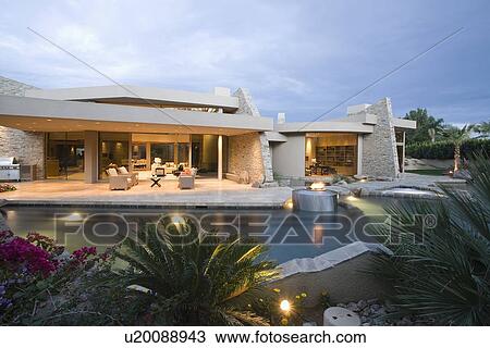 Stock Image - Palm Springs swimming pool and house exterior at dusk. Fotosearch