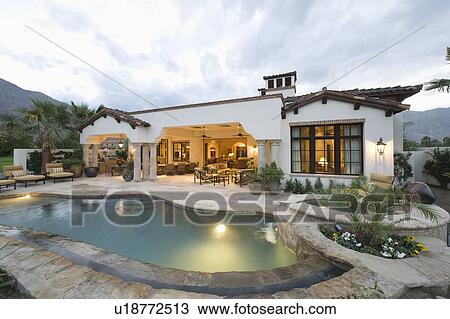 Stock Image - Poolside and lit interior of Palm Springs home. Fotosearch