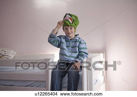 Picture - Portrait of boy holding mask on bed. Fotosearch