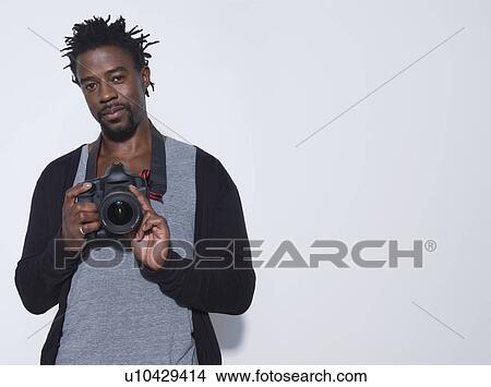 Picture - Portrait of mid adult (30-35 years) photographer holding camera studio shot. Fotosearch
