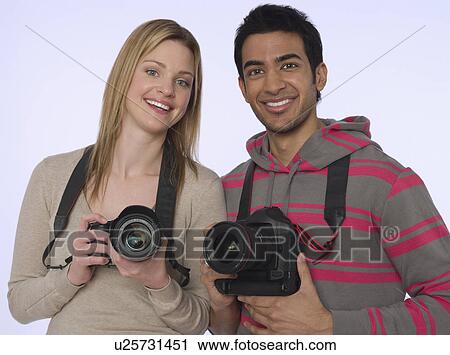Stock Image - Portrait of young photographers with cameras studio shot. Fotosearch