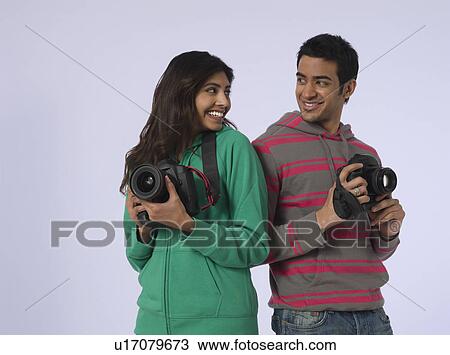 Portrait of young woman and young man holding cameras studio shot View Large Photo Image Stock Image - Portrait of young woman and young man holding cameras studio shot. Fotosearch