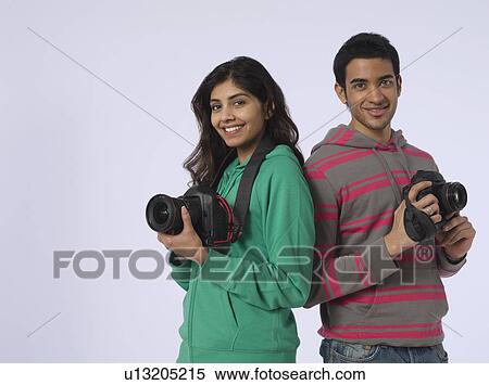 Portrait of young woman and young man holding cameras studio shot View Large Photo Image Stock Photography - Portrait of young woman and young man holding cameras studio shot. Fotosearch