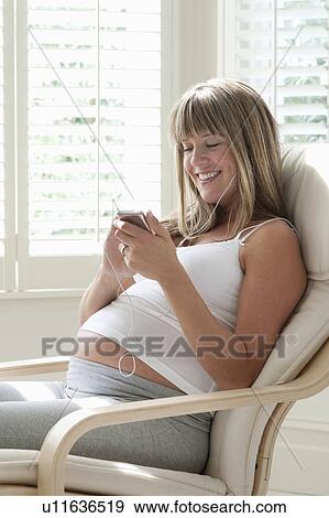Pregnant woman listening to music on MP3 player View Large Photo Image Stock Photo - Pregnant woman listening to music on MP3 player. Fotosearch