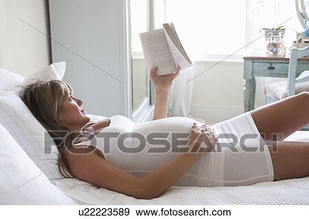 Pregnant woman lying on bed reading book View Large Photo Image Stock Photo - Pregnant woman lying on bed reading book. Fotosearch