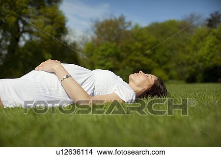 Pregnant woman lying on grass View Large Photo Image Picture - Pregnant woman lying on grass. Fotosearch