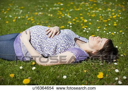 Pregnant woman lying on grass View Large Photo Image Picture - Pregnant woman lying on grass. Fotosearch