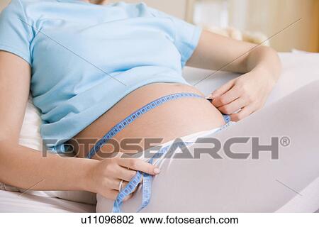 Pregnant woman measuring stomach on bed View Large Photo Image Stock Image - Pregnant woman measuring stomach on bed. Fotosearch