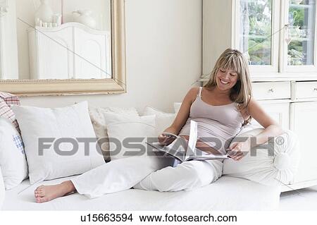 Pregnant woman reclining on sofa with book View Large Photo Image Picture - Pregnant woman reclining on sofa with book. Fotosearch