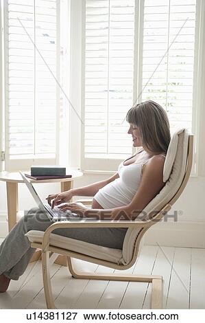 Pregnant woman sitting on chair using laptop View Large Photo Image Stock Photo - Pregnant woman sitting on chair using laptop. Fotosearch